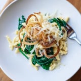 Hausgemachte Spätzle in leckerer Spinatsauce, serviert mit schmelzendem Käse und Zwiebeln.  