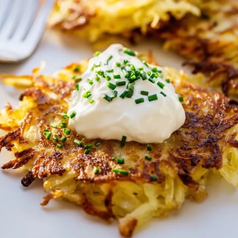 Knusprige, goldene Kartoffelpuffer mit einem Klecks frischer Saurer Sahne – ein herzhaftes, amerikanisches Gericht.