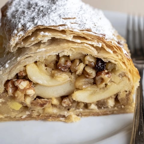 Klassischer deutscher Apfelstrudel mit flaumigem Teig, gefüllt mit süßen, gewürzten Äpfeln.